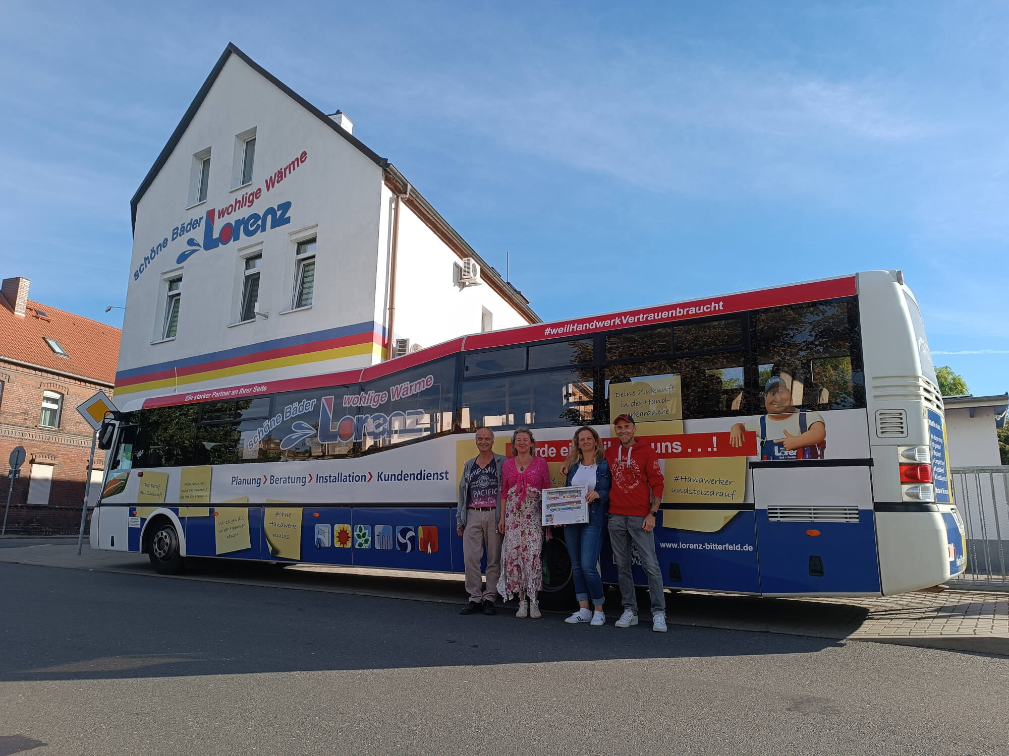 Dieses Bild zeigt vier Mitarbeiter vor einem Bus welcher mit Werbung für Lorenz bedruckt ist