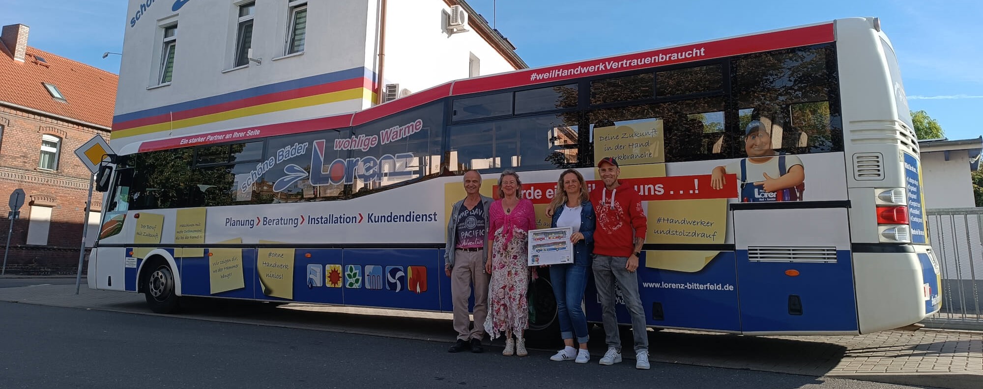 Dieses Bild zeigt vier Mitarbeiter vor einem Bus welcher mit Werbung für Lorenz bedruckt ist
