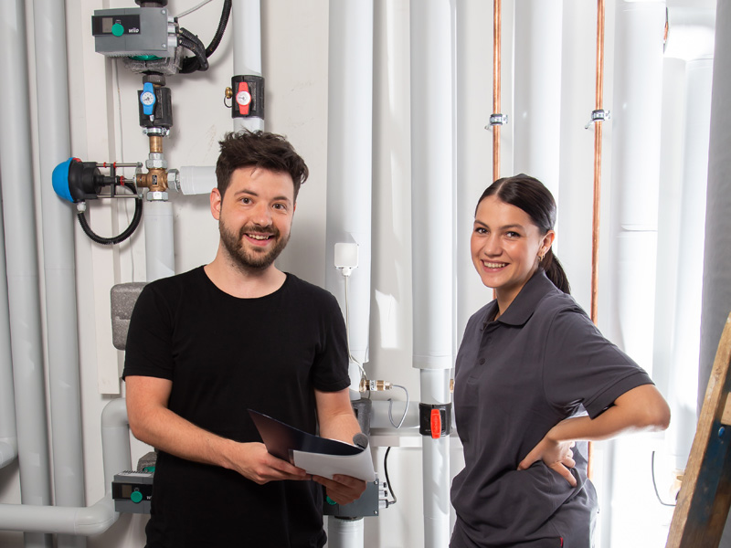 Dieses Bild zeigt zwei Mitarbeiter mit dem Beruf Kunden­dienst­mon­teur/-in (m/w/d) für Sanitär-, Hei­zungs- oder Klima­technik.